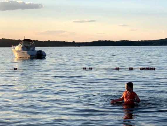 girl swimming in lake with boat in background (Instagram@saratedidee)