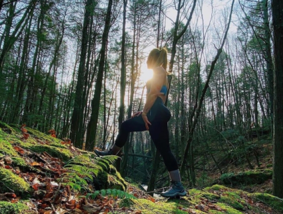 A woman hiking up hill through the woods in the fall