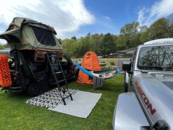 A jeep and camper on a field in summer (Instagram@jeepin_new_england)